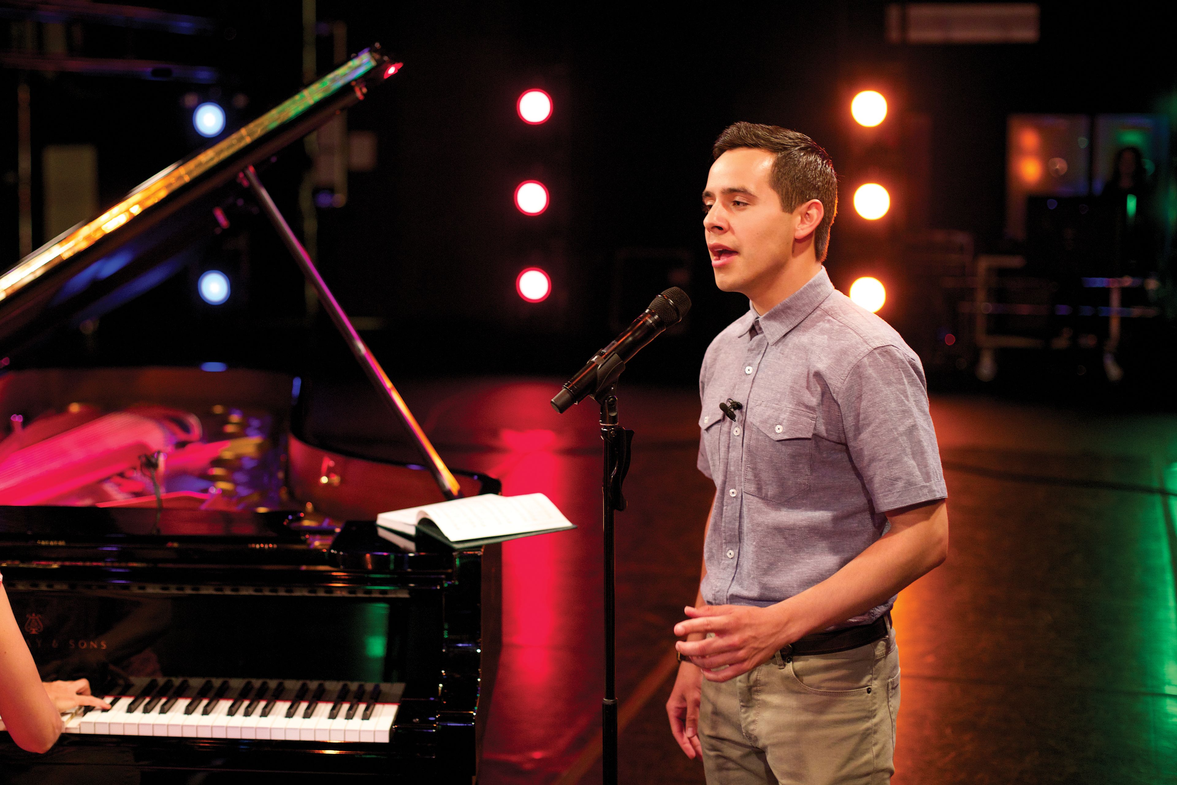 David Archuleta sings while standing next to a piano.