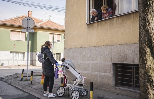 woman on a walk talking to women at window