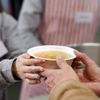 one person handing another a bowl of soup