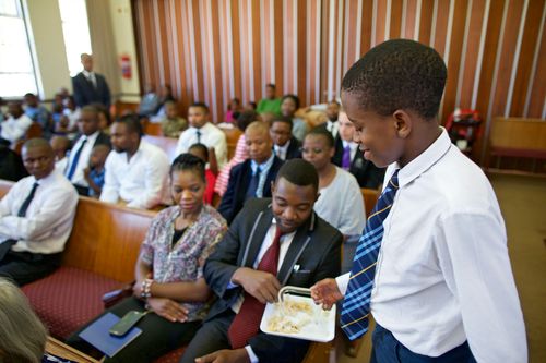 young man passing the sacrament to members in church