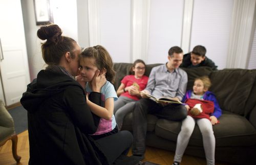 A mother holds and plays with her daughter.