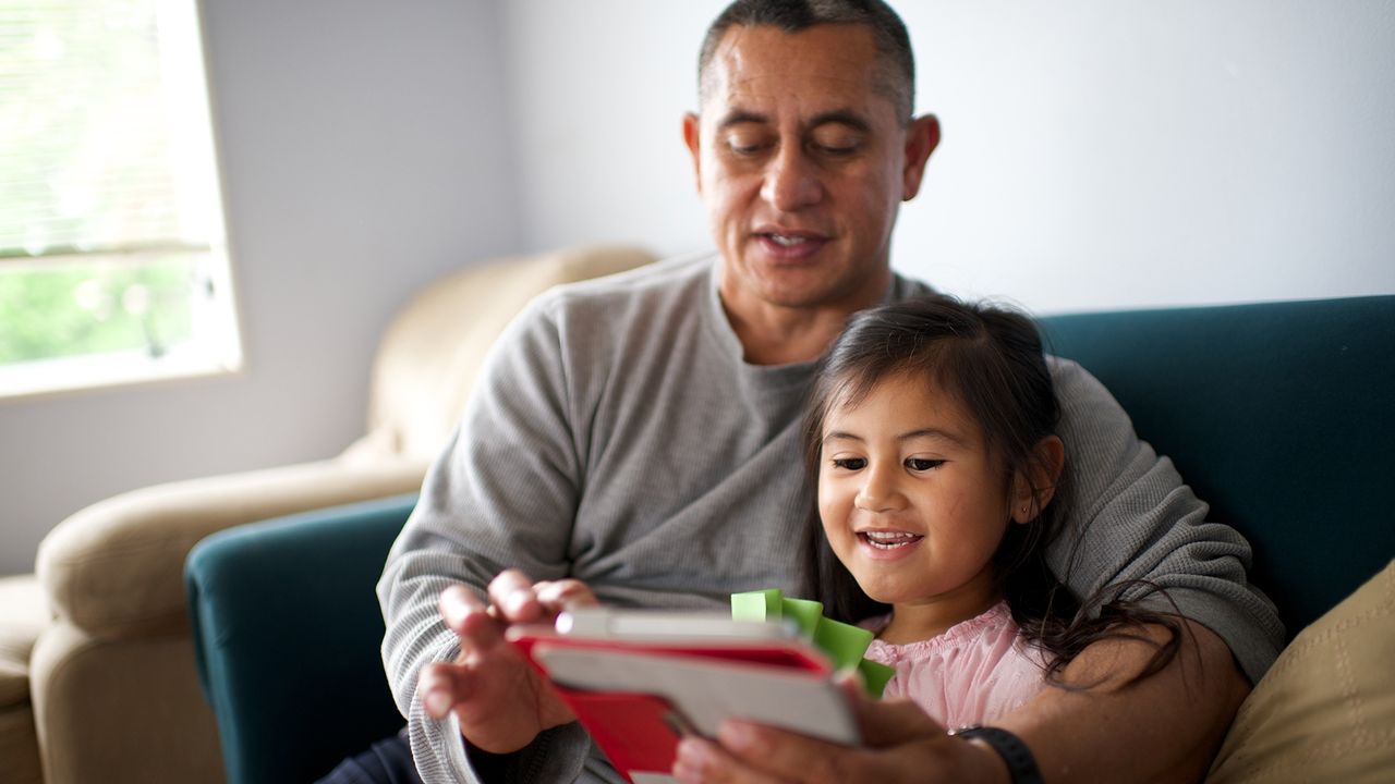 Fillette et son père lisant la Bible sur une tablette