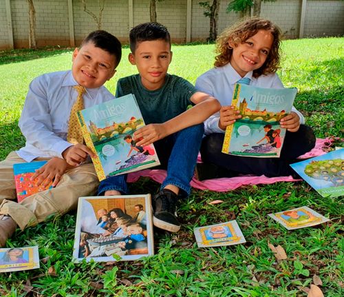 Three children holding the Friend magazine outside