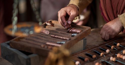 Scenes from an outdoor market, money changer’s table with coin trays. Outtakes include coins in pan of a balance scale, clay lamps that are lit on a ledge, and some chickens.