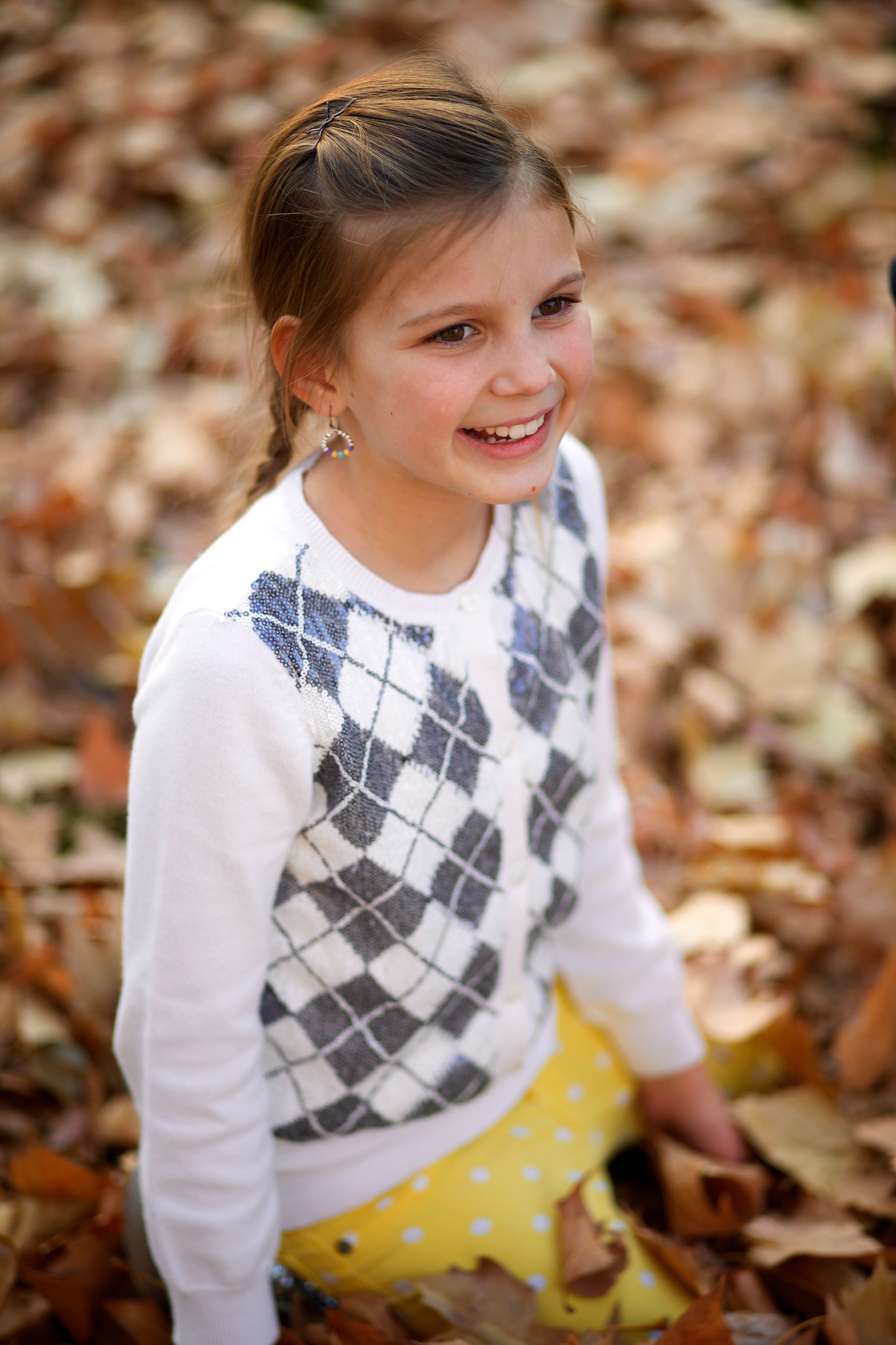 A young girl is playing in a pile of leaves in the fall.