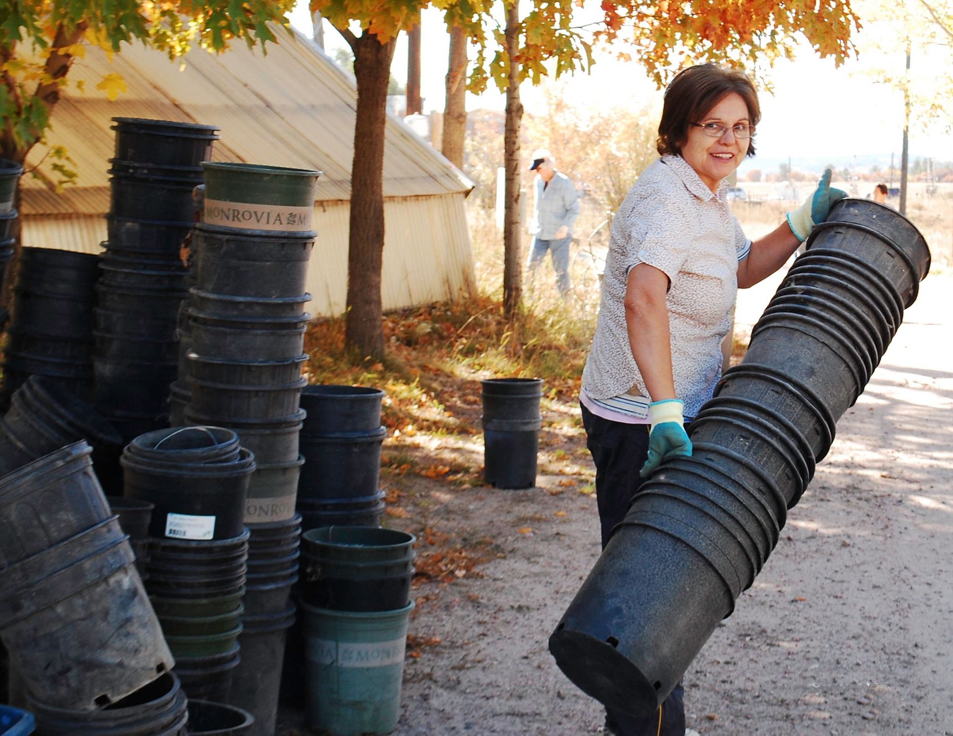 A woman carrying a stack of planting buckets for a ward service project.