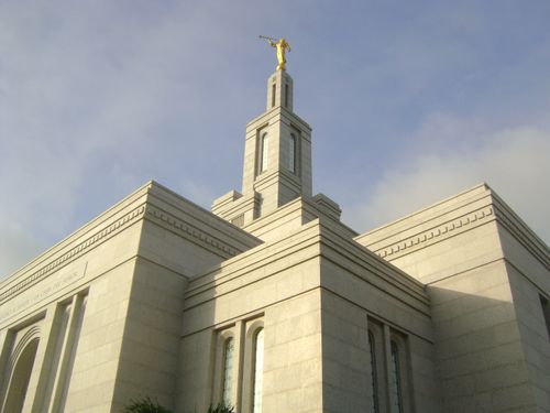 A view of the Panama City Panama Temple from below, looking up toward the spire, with a pale blue sky above.