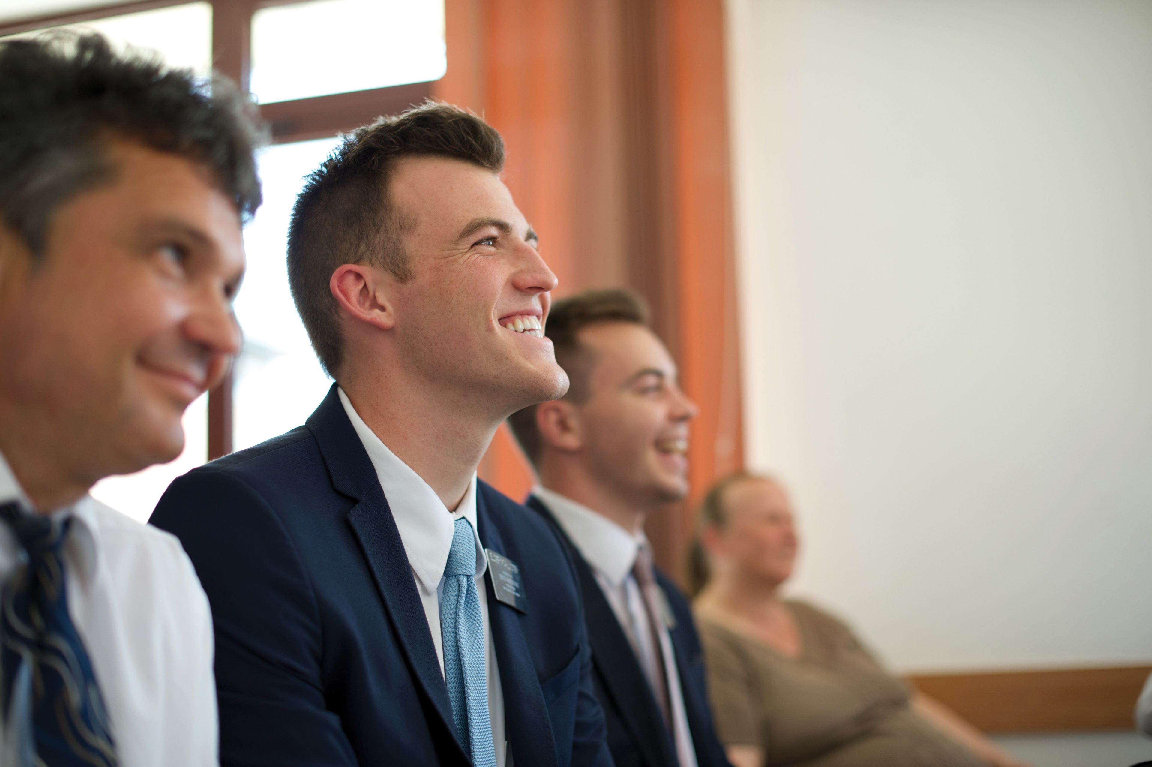 Elder missionaries smiling during a Church meeting.