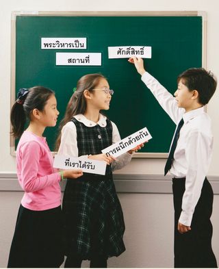 two girls putting word strips on chalkboard