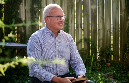 man smiling and holding a book