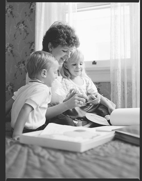 A mother studying scriptures with two young children