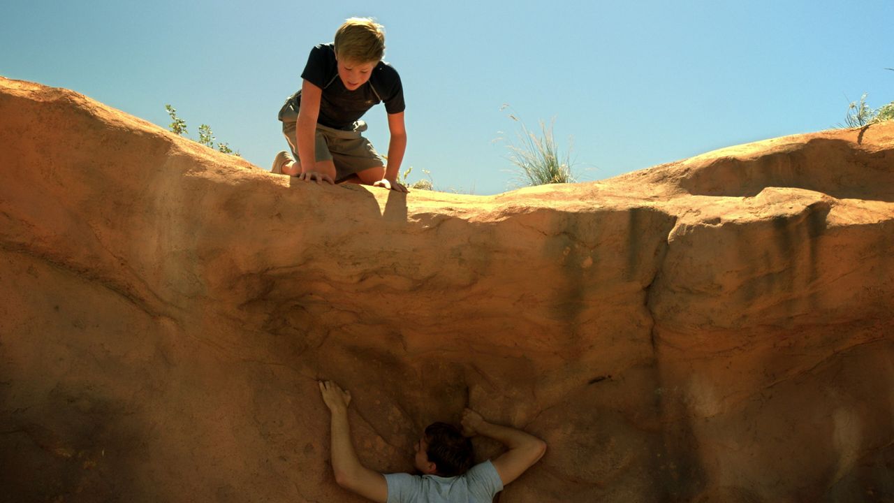 Two brothers attempt to climb a sheer canyon wall without any safety ropes or harnesses.