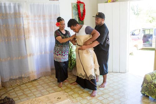 a man being helped by others to put on traditional clothing