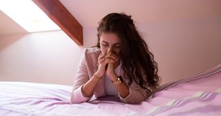 girl praying by a bed