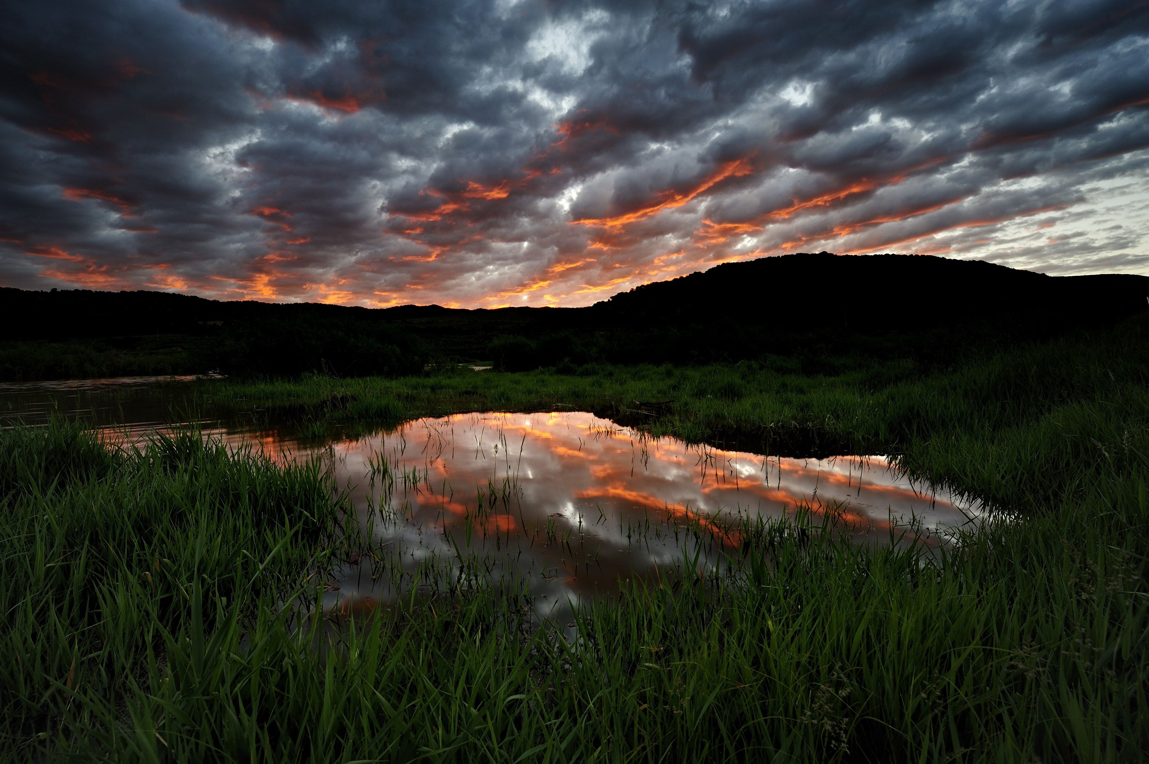 The sun rises over mountains and a pond in Utah.