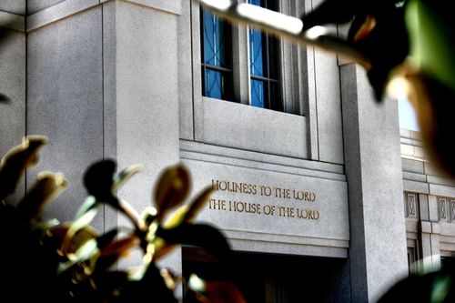 The inscription on The Gila Valley Arizona Temple, “Holiness to the Lord: The House of the Lord,” viewed through trees on the grounds.