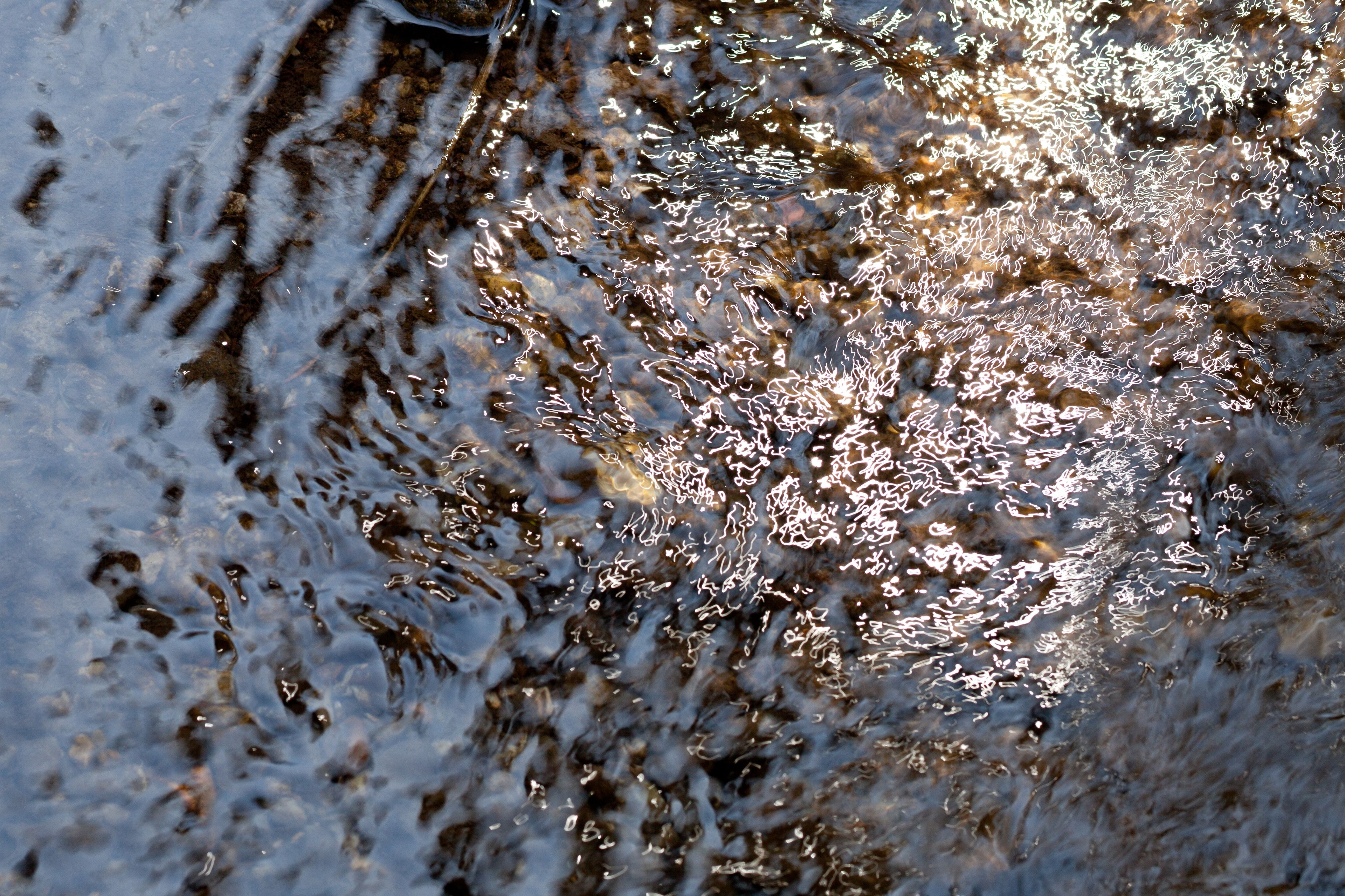 Small ripples in opaque river water, barely showing the stones below.