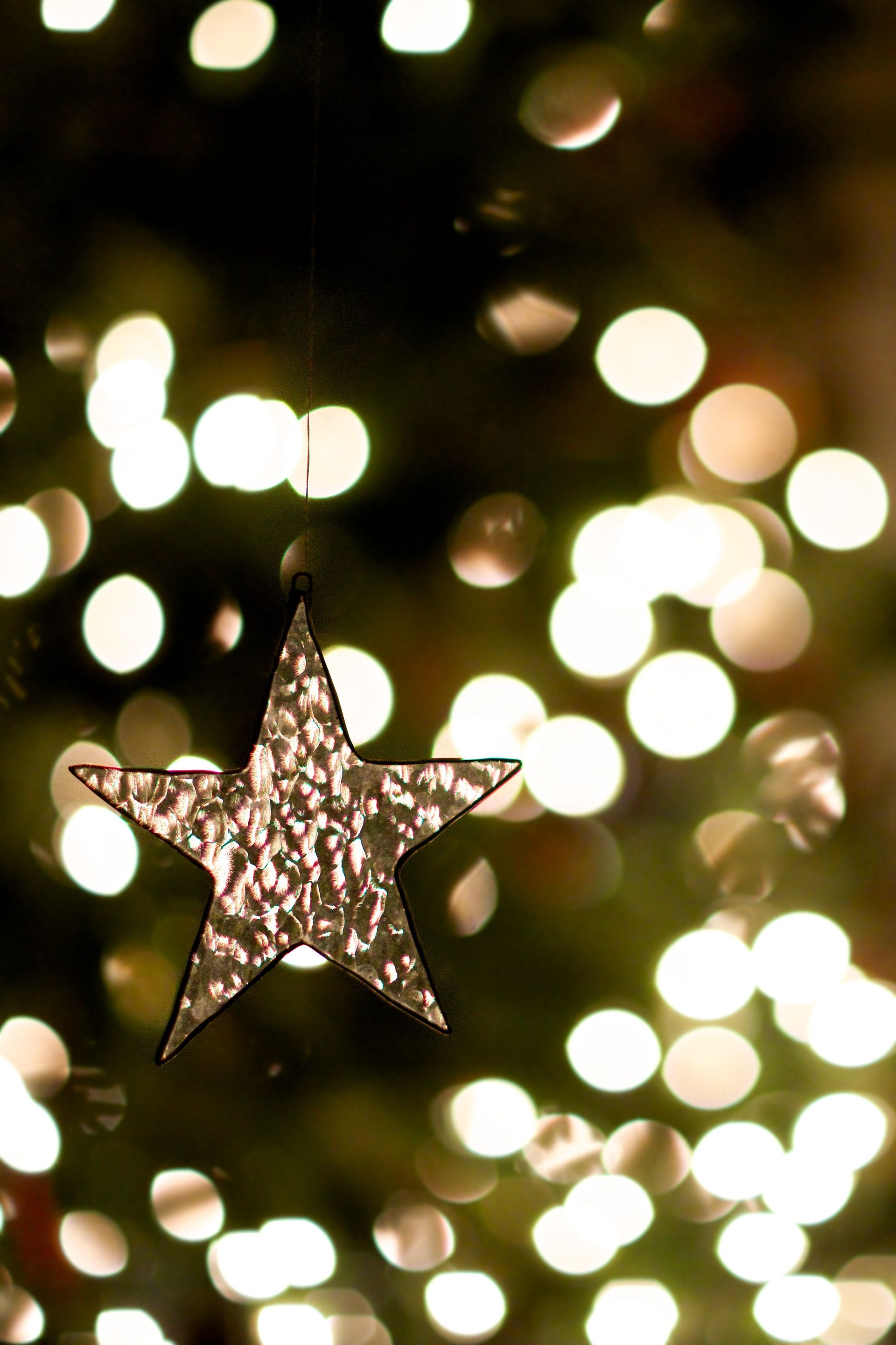 A small glass star ornament hanging from a Christmas tree.