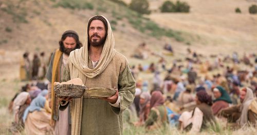 Jesus blessing bread he is about to feed to the gathered multitude.