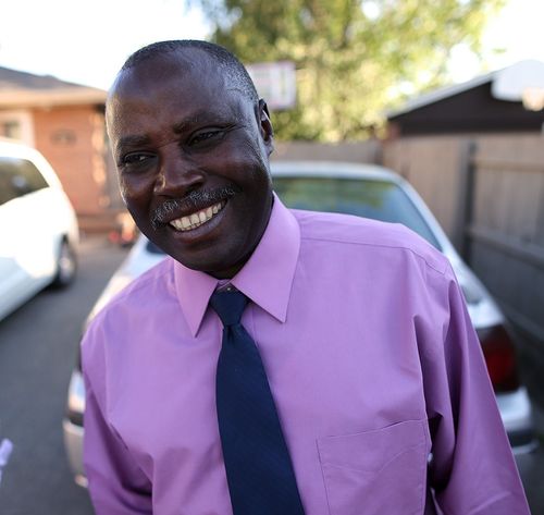 man smiling in purple shirt and tie