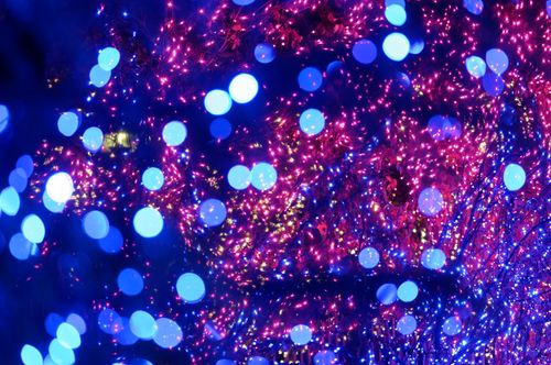 A close-up view of pink, purple, and blue Christmas lights at night.