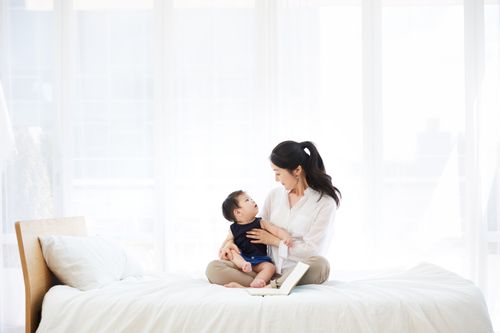 mother and baby sitting on bed