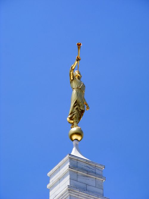 The angel Moroni statue seen atop the Raleigh North Carolina Temple on a clear day with a bright blue sky in the background.