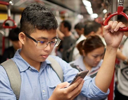 man looking at phone on train