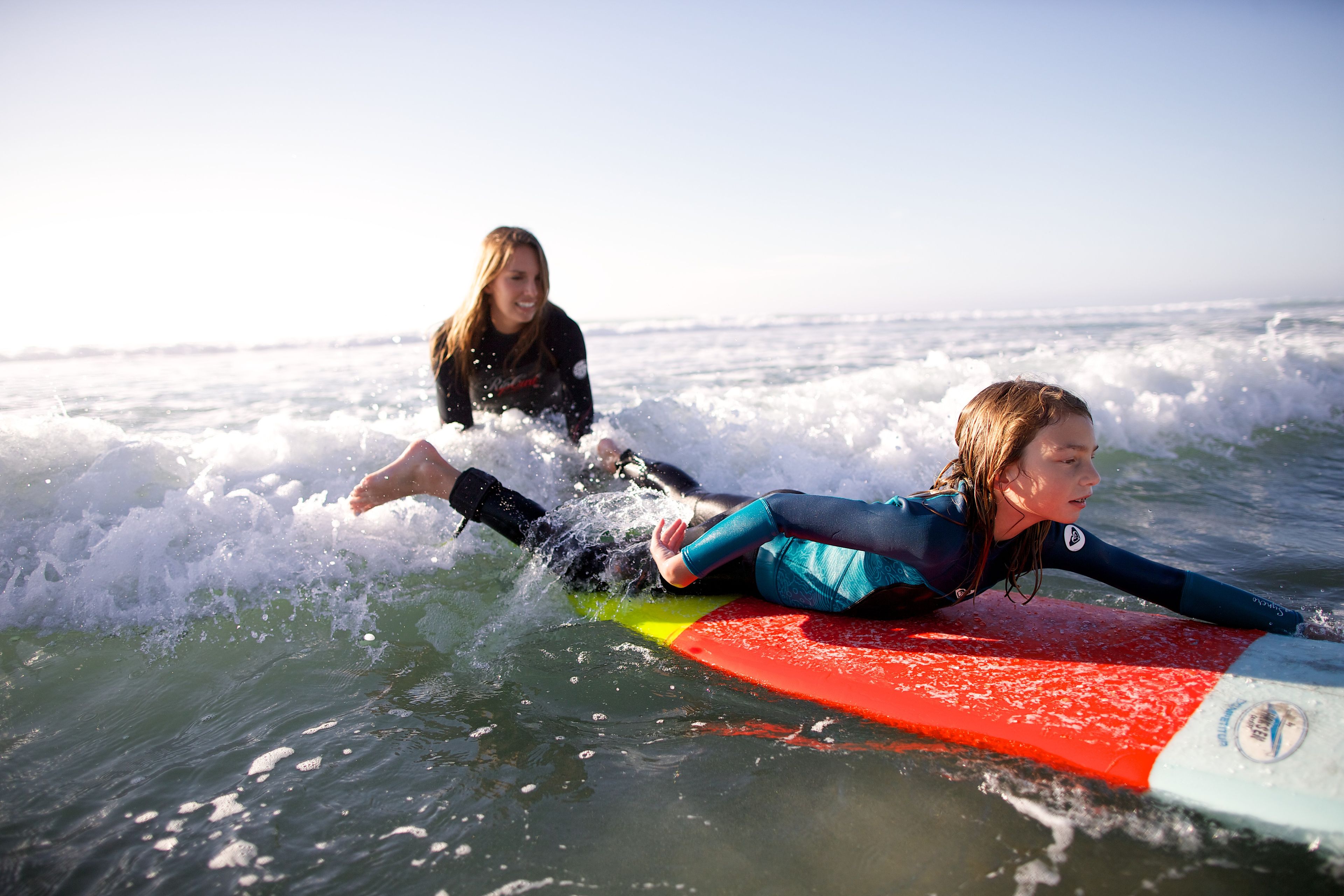 A mother and daughter go surfing together.