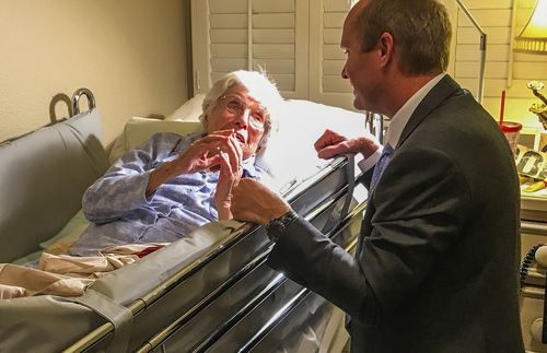 man at bedside of elderly woman