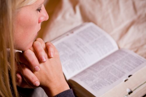 young woman with scriptures praying