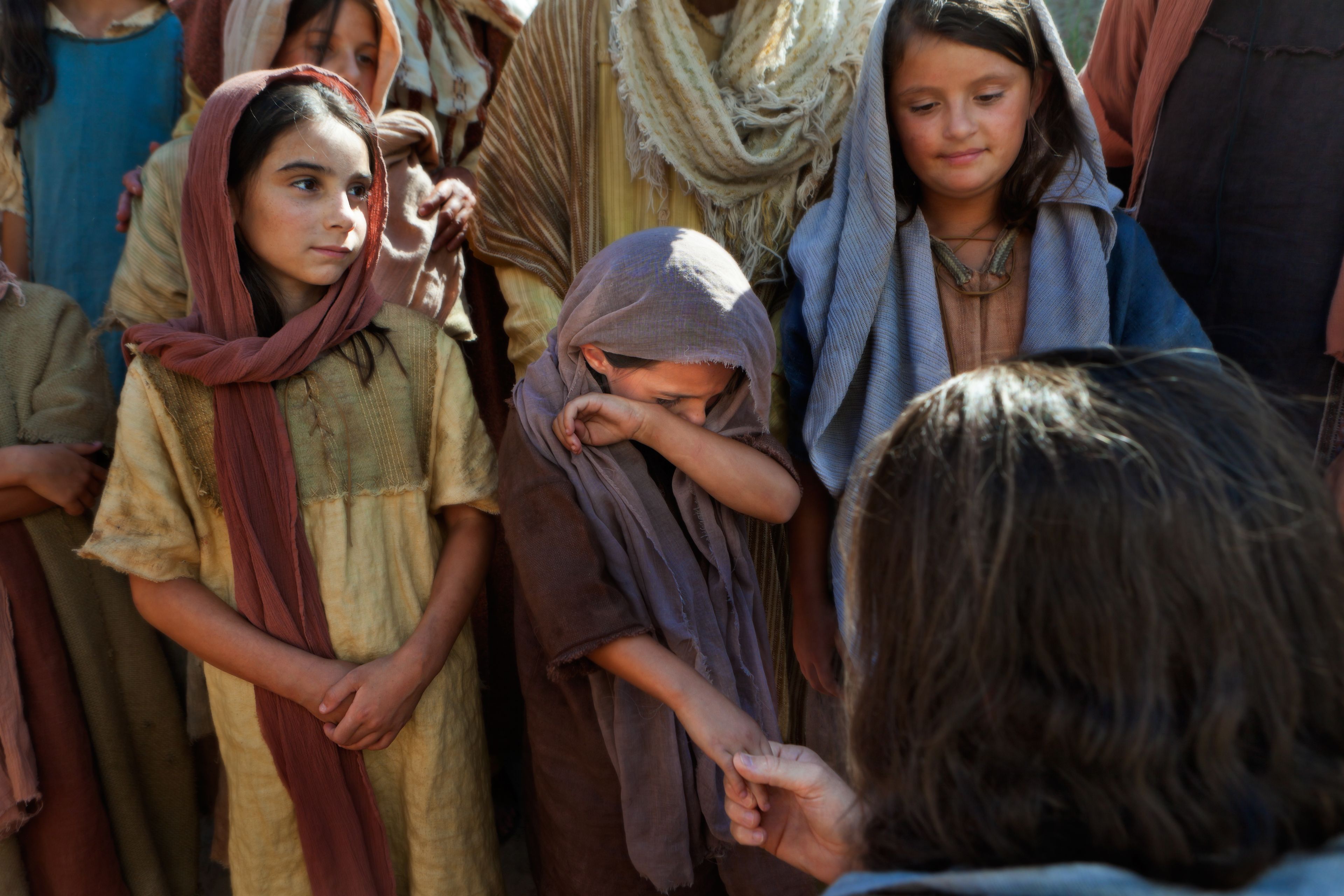 Cristo habla con un grupo de niños, uno de los cuales está llorando.