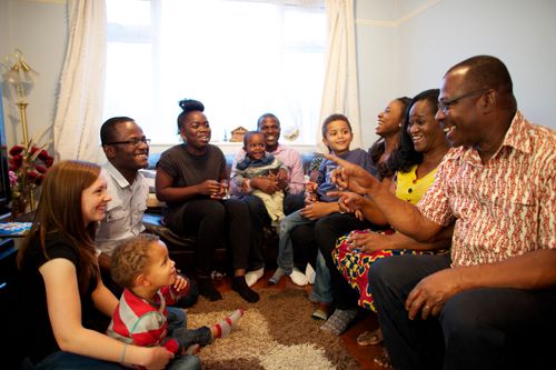 An extended family sits and talks together in a living room during a family home evening.