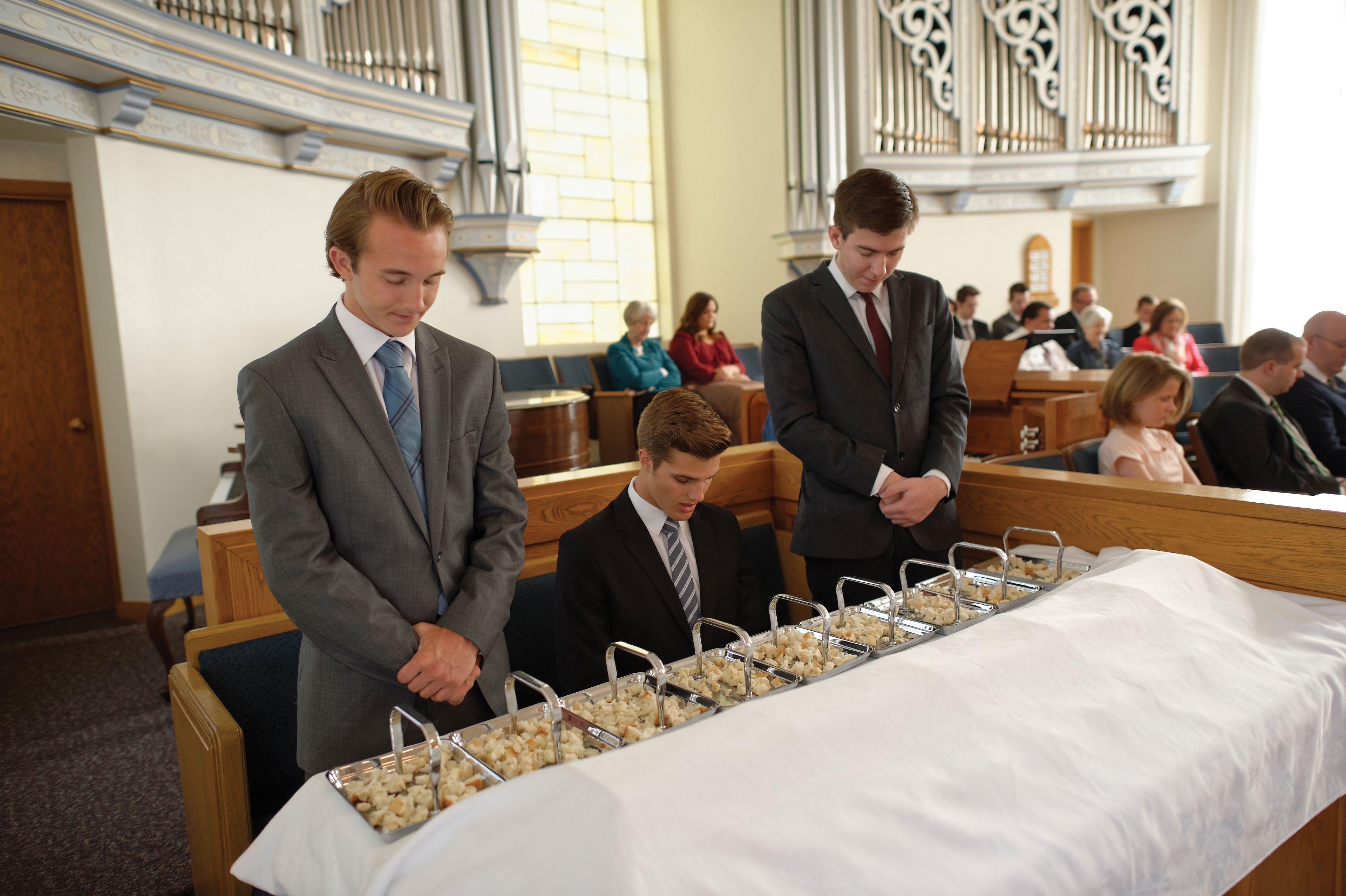 Three young men blessing the sacrament bread for the congregation.