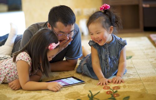 father and girls looking at tablet