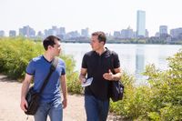 Young adult man holding and talking about the Book of Mormon to another man.