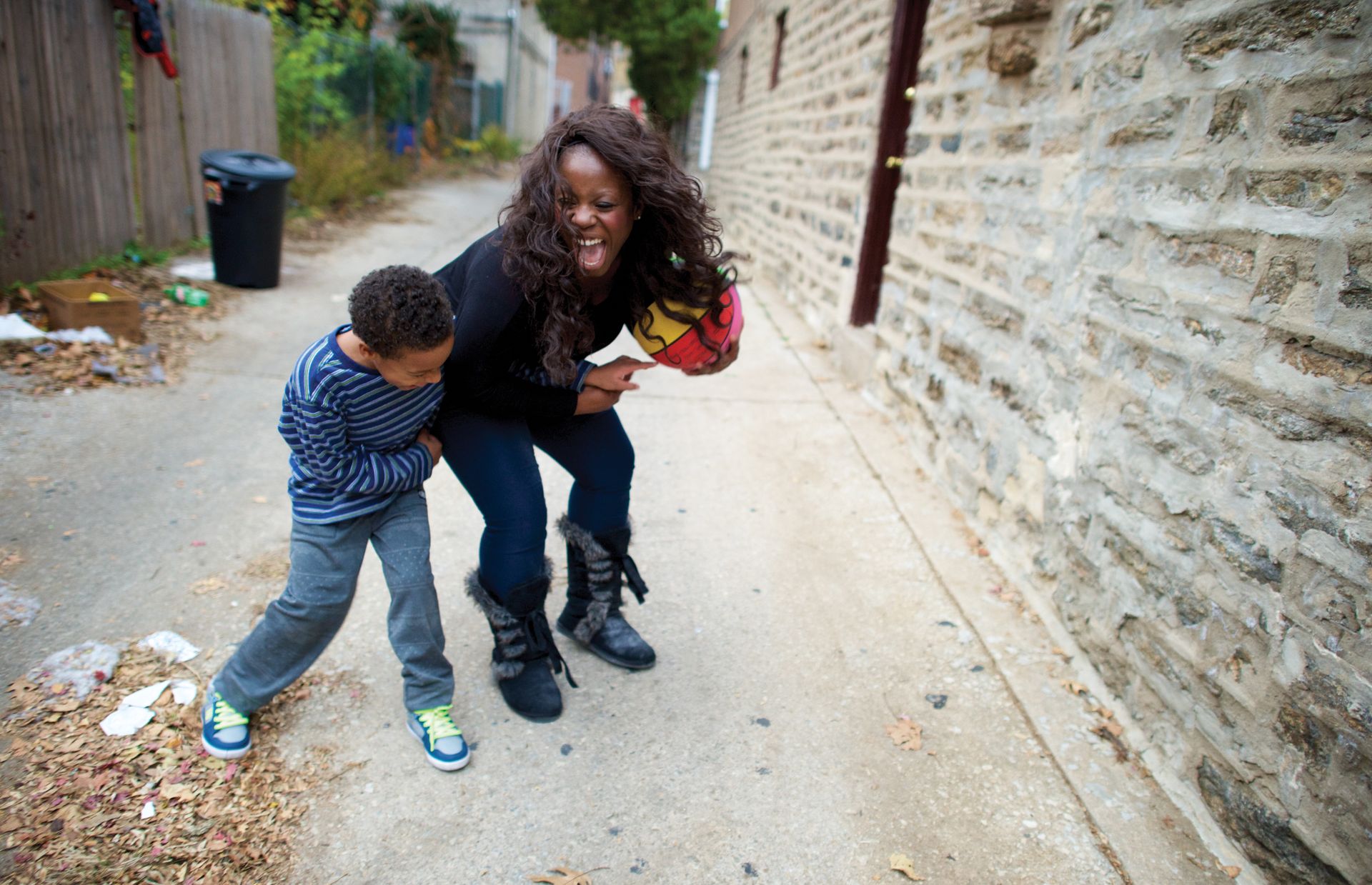 Enoch takes a break from his homework to play basketball with his mother outside their home in Philadelphia.