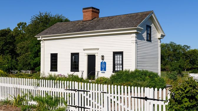 White clapboard home with white picket fence in front.