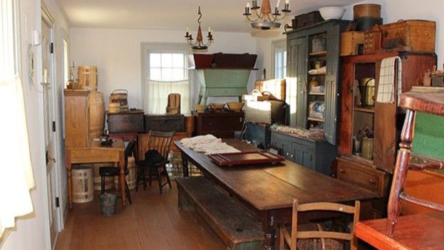 Narrow room with many furnishings and artifacts packed along the walls.