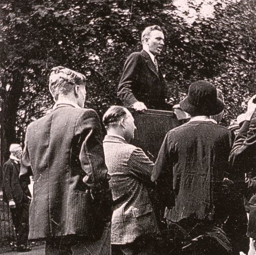 A black and white image of Gordon B. Hinckley as a young missionary speaking to a crowd.