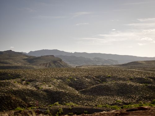 Mountains in the desert covered with brown and green brush.
