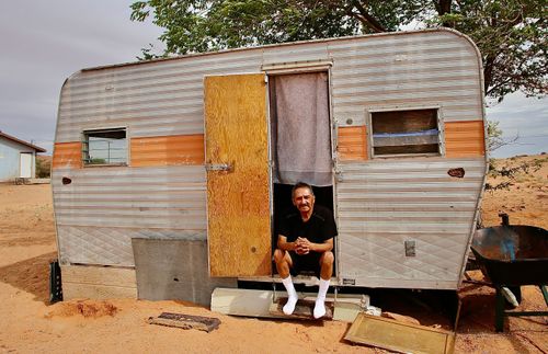 man sitting in the entrance to his trailer