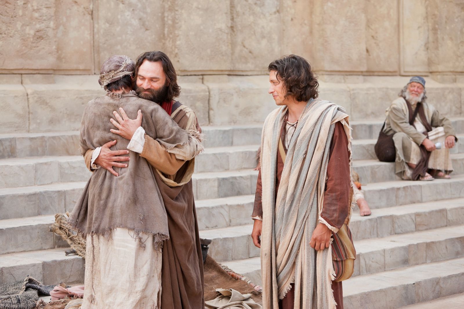 A man crippled since birth is healed by Peter and John, and he thanks them with an embrace.