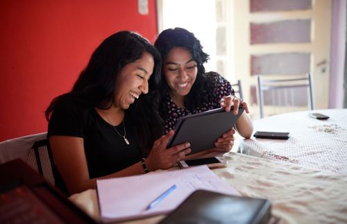 two women looking at a tablet and smiling