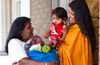 una mujer lleva comida a una madre y a su hijo