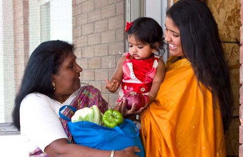 woman bringing food to a mother holding a child