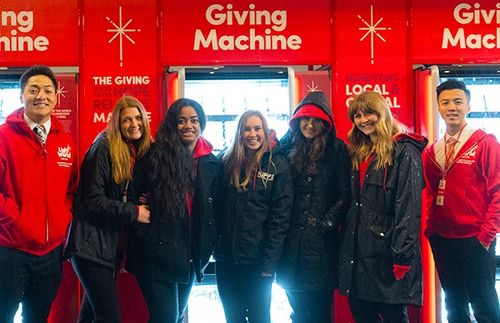 group of young adults in front of the Giving Machines at Christmastime