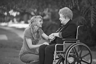 Young woman talking to older woman in wheelchair