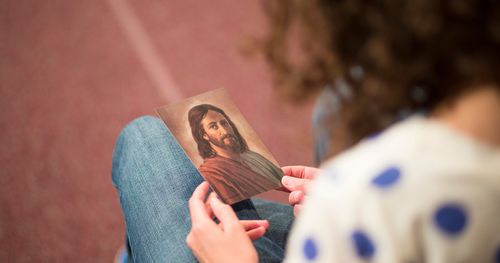 A woman holding a small picture of Jesus Christ. The picture is a reproduction of a painting by Robert Barrett.