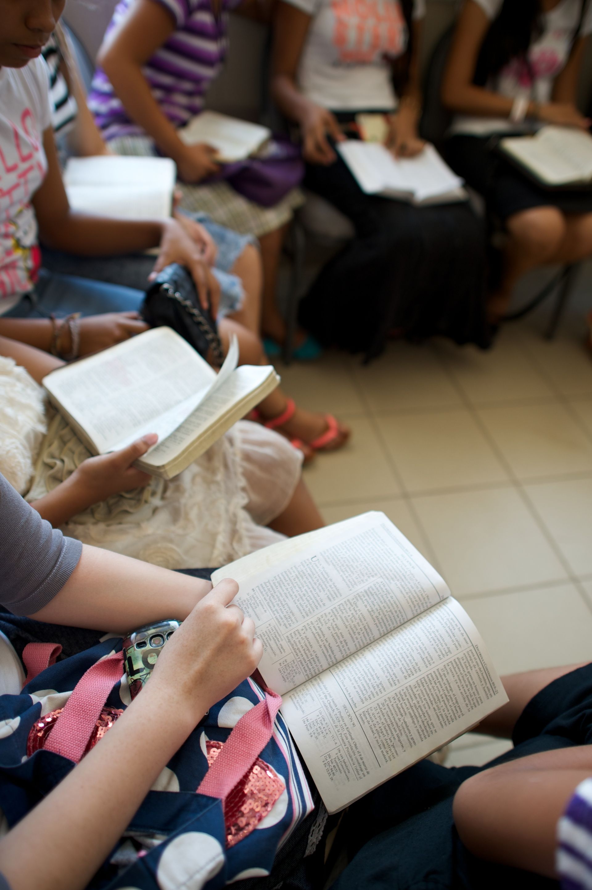 A group of youth sitting in a circle and reading from scriptures.